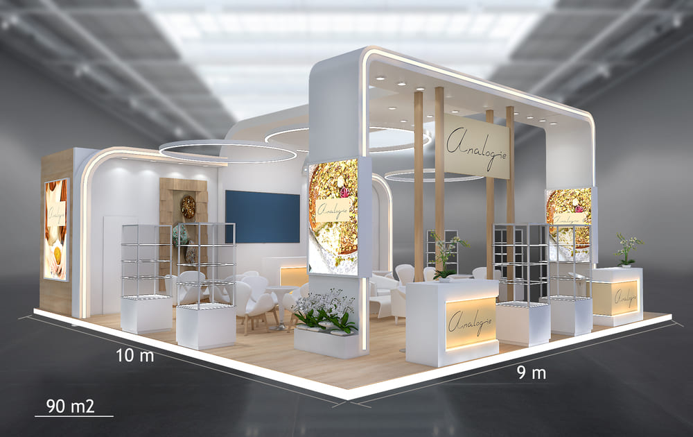 Stand de 90 m² (9 × 10 m) : îlot ouvert sur quatre faces, espace lounge et zone de démonstration.